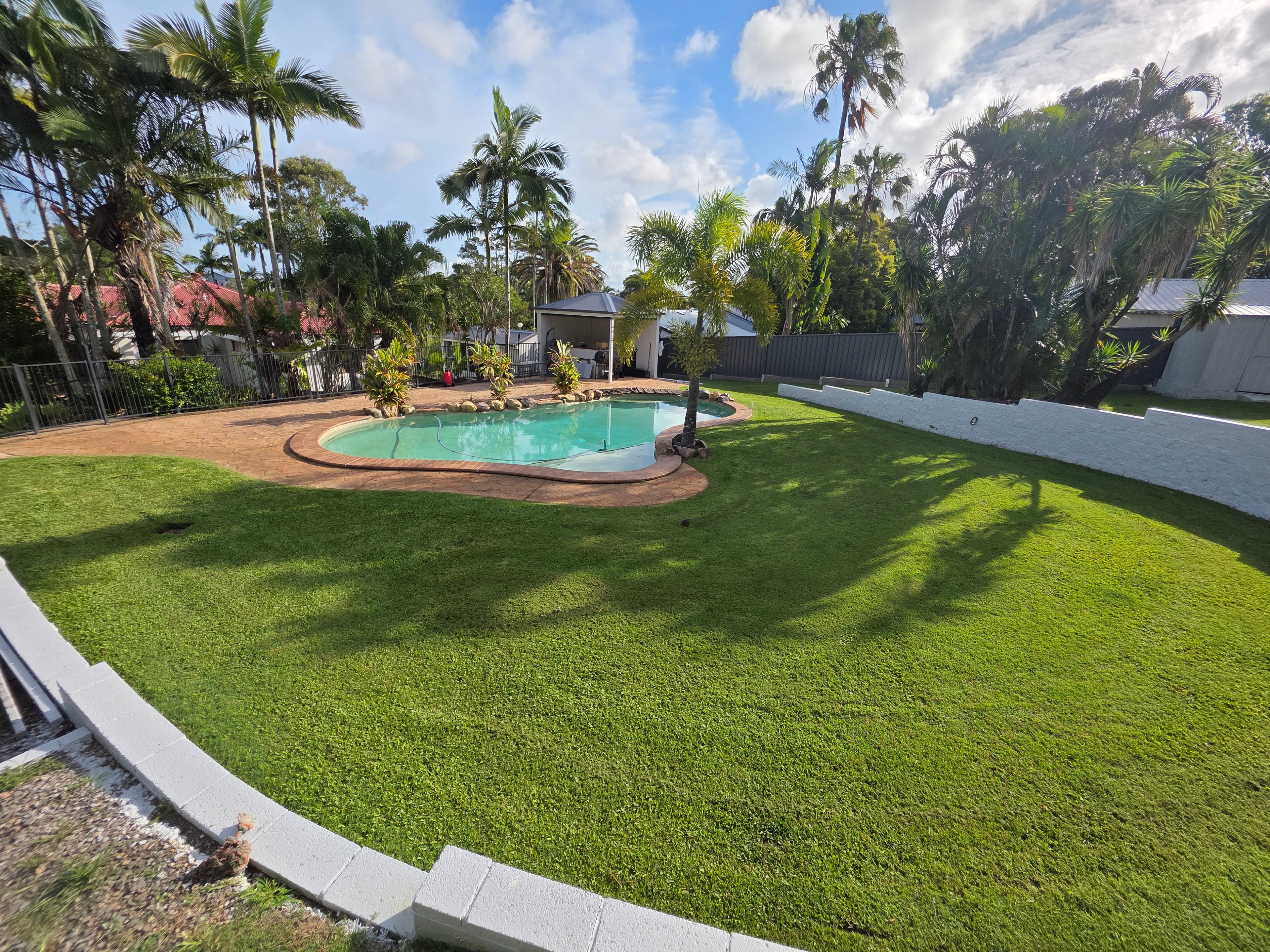 Residential pool area with lush green lawn